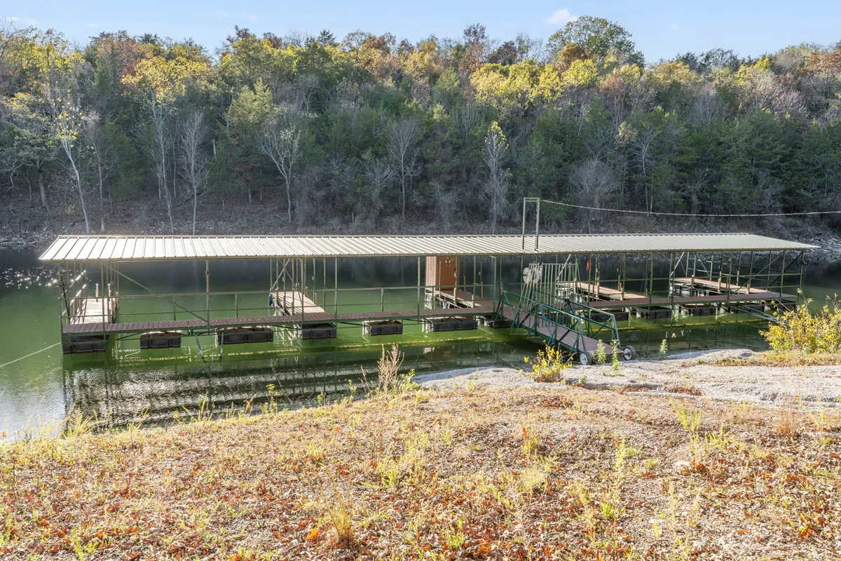 This image spotlights a peaceful boat dock extending into calm water, bordered by foliage and set against a tranquil lakeside backdrop. The dock invites boating, fishing, and quiet lakeside moments, echoing the direct lake access described in the section.