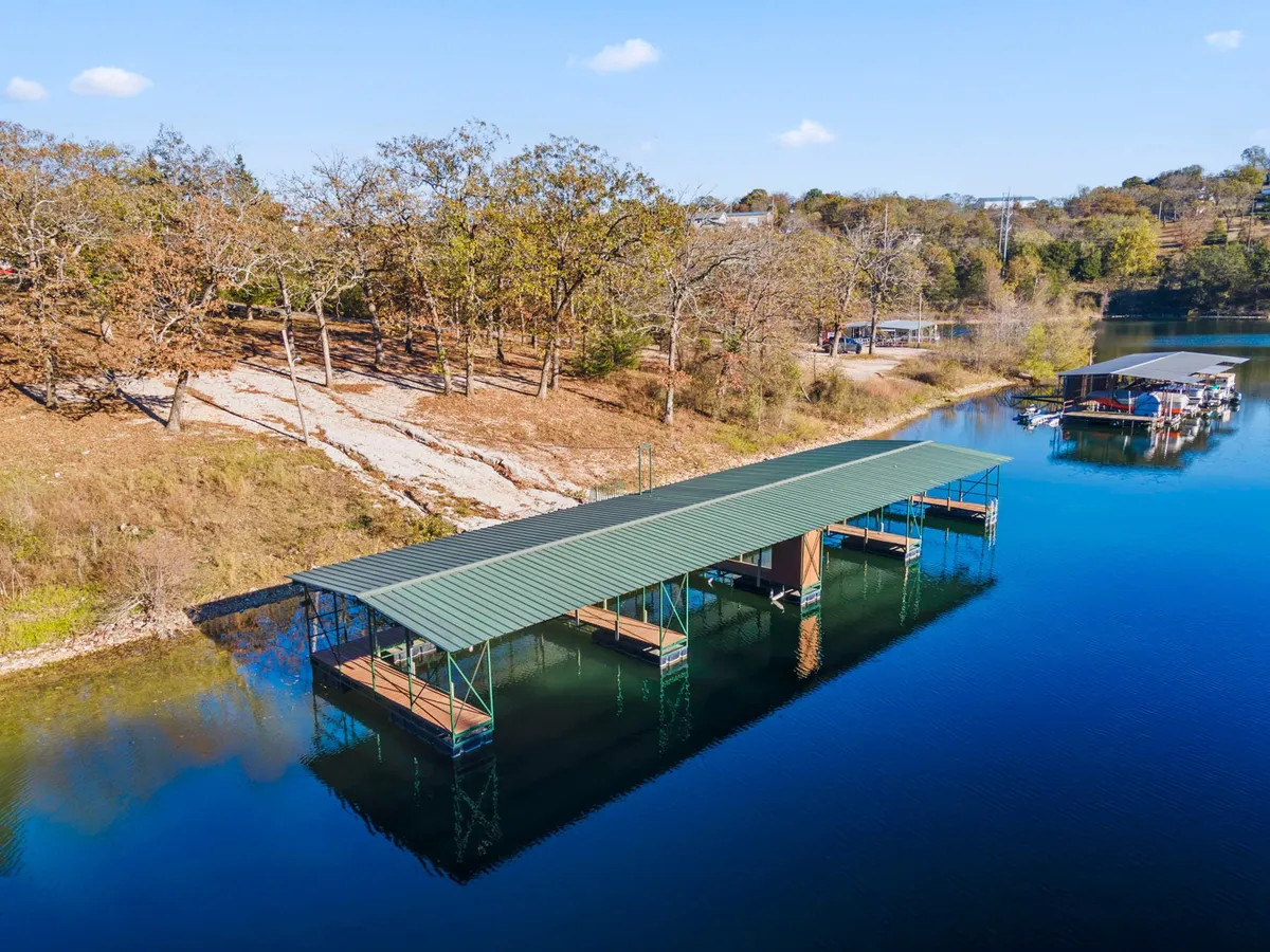 A tranquil dock extends into clear water, surrounded by lush trees and open landscape. The scene suggests fishing, boating, or simply enjoying peaceful moments by the lake, with hints of wildlife and natural beauty.